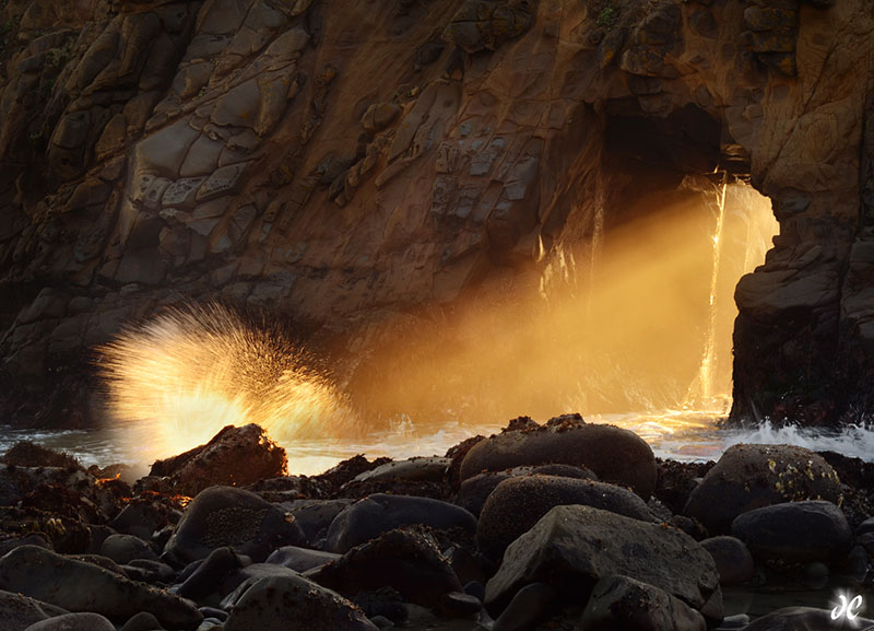 Sunlight shines through the arch at Pfieffer Beach in Big Sur, California