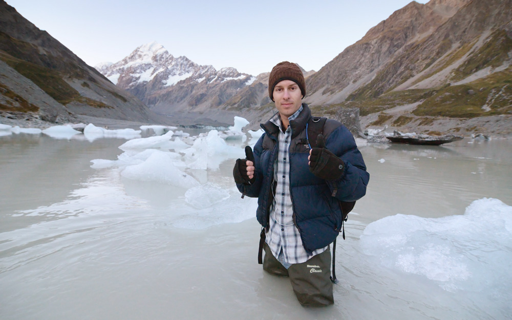 photographer standing in Hooker Lake, Mt. Cook National Park, New Zealand