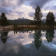 Unicorn Peak and Cathedral Peak reflected in a pool in the Tuolumne River during a stormy sunset
